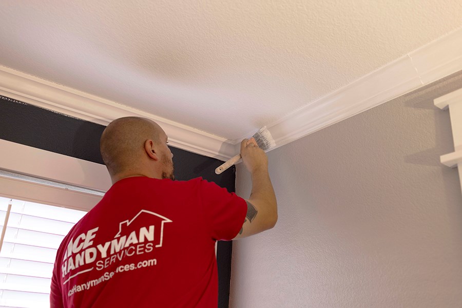 An AYGU HANDYMAN painting a window trim