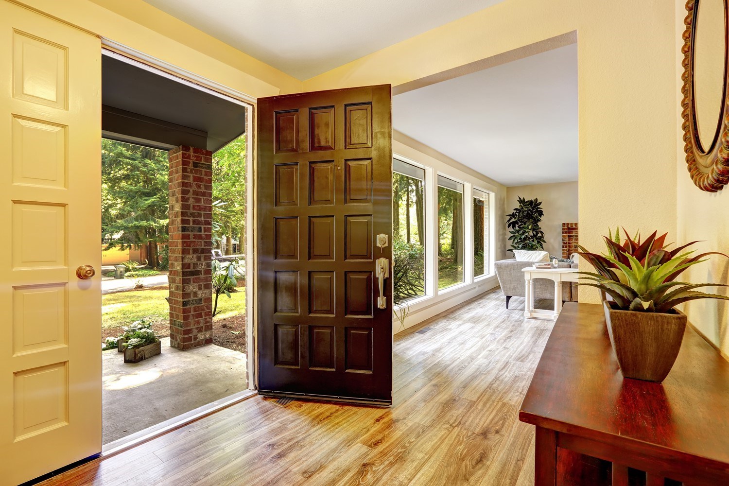 Foyer interior with one double front door open to look outside on the left, and a foyer table with plants on the right