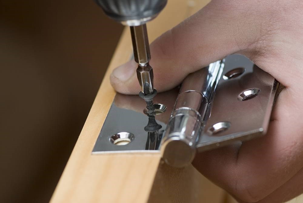 someone attaching a door hinge to a door