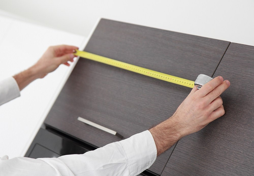 image of someone measuring a kitchen cabinet