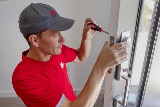 A handyman installs a door in a house