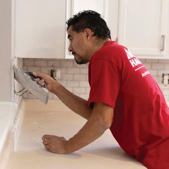 A Handyman works to complete a kitchen remodel project A Handyman works to complete a kitchen remodel project