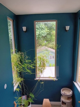 Outdated cream and brown light fixture on staircase wall. The lights are on either side of a long window with a view of the Arcata neighborhood.