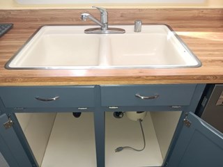 White cast iron sink before replacement. The faucet and dishwasher airgap are stainless steel and the cabinets and drawers are painted blue.