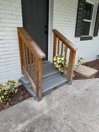 Exterior stair railings before painting, showing faded and weathered surfaces on the front door steps.