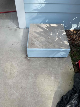 Repaired exterior cement podium with new wood trim painted to match the home, fully refreshed for decorative outdoor displays.