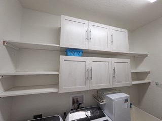 Laundry room storage after custom-built wood shelving and cabinets are installed