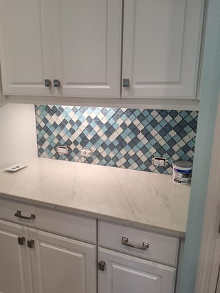 Kitchen wall after installation of tile backsplash, including grouting. 