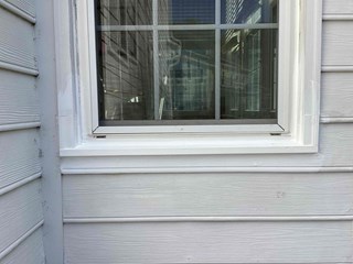 he same window with the damaged area now repaired. The peeling paint has been removed, and the trim around the window is freshly painted and smooth. 