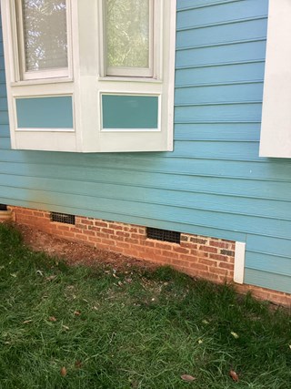 The same side of the house, but now the damaged wood has been replaced. The wood beneath the bay window appears intact and undamaged. 