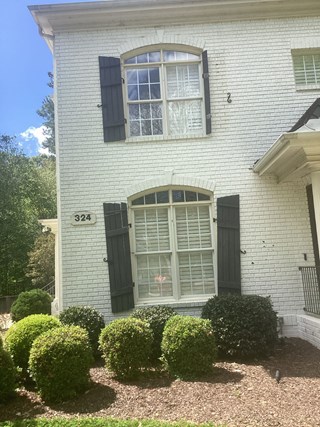 A brick building with a shutter missing on the second floor. 