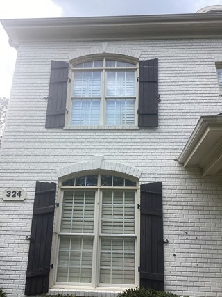 A brick building with a shutter replaced on the second floor. 
