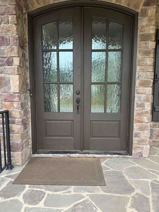 Door after it has been repainted. The door now has a fresh, smooth finish with a darker, more modern color. The surface is free of scratches, and the overall appearance is more polished and well-maintained, enhancing the entryway's aesthetic.