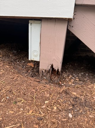 The wooden post is visibly rotted, with a significant portion of it missing, which could affect the structural integrity of the porch.
