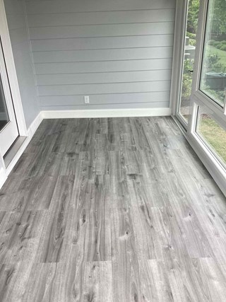 Floor after it has been updated with new flooring. The floor now has a clean, modern look with gray laminate planks that add a polished, finished appearance to the space.