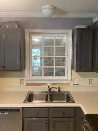 Kitchen area with a window above the sink, with a section of the wall and countertop visible. The area around the window has not been finished