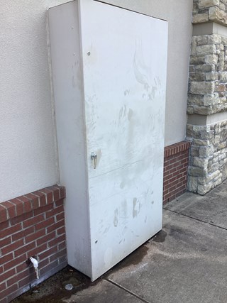 An outdoor commercial storage unit that is stained and dirty, with visible handprints and marks on the surface. The unit's appearance is weathered, and it has accumulated dirt or smudges on its white exterior.