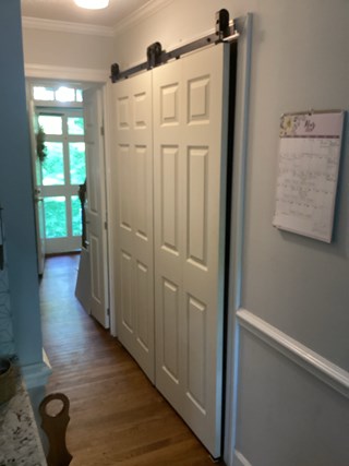 Laundry closet area transformed with a new sliding door installation. The door is now a smooth, modern design with a rail above for sliding functionality.