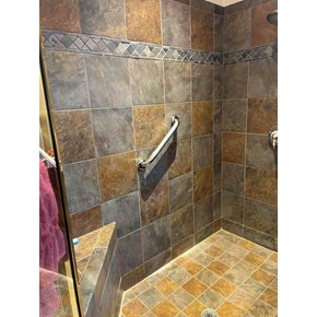 A close-up view of a bathroom or shower wall with a grab bar installed.