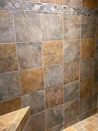 Tiled shower wall with a decorative tile border, but without any additional features such as grab bars or other hardware.