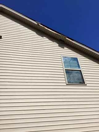 Exterior wall with visible damage to the fascia near the roofline.