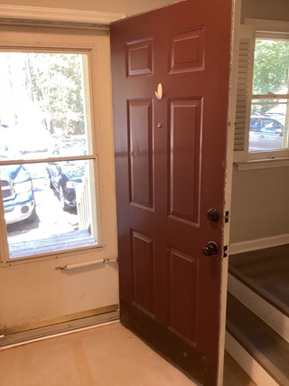 Entry door with a partially exposed frame. The door is in need of repair, and there is some visible damage around the door's edges.