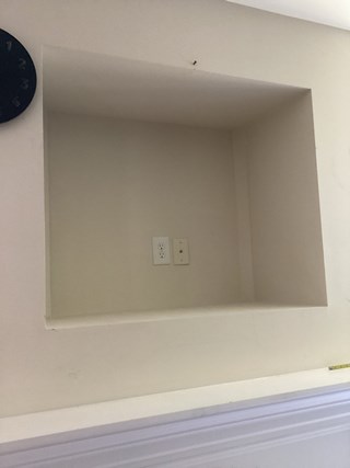 Small alcove in a wall with exposed electrical outlets. The drywall around the alcove is in good condition, but the area is unfinished, with the back of the alcove bare and unpainted.