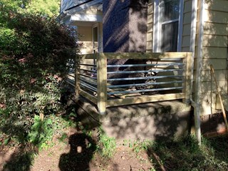 The new railing features wooden posts and horizontal metal bars that offer a more modern and sleek design compared to the previous vertical spindles.