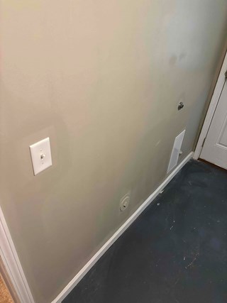  The drywall has been replaced and finished, and the wall appears smooth and intact with no signs of the previous cutout. The area looks fully restored, and the surrounding space is clean and well-maintained.