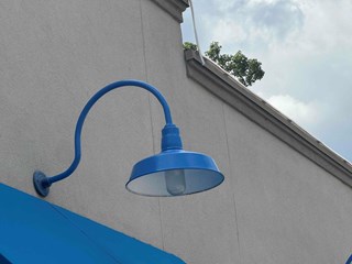 Commercial exterior light fixture after it has been repainted. The fixture is now a bright and uniform blue, with no visible signs of fading or wear, giving it a freshly painted look.