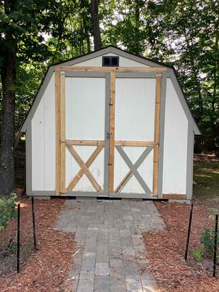 Shed with new framing around the doors. New wood has been added along the edges, enhancing the structure and appearance of the doors, and reinforcing the design. 