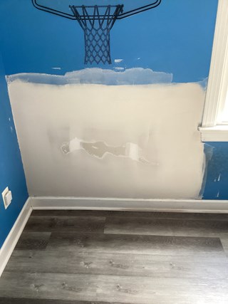 The damaged drywall has been patched and smoothed out. The surface is ready for repainting, and the patched area looks clean and even, with no visible damage or peeling. The overall wall is now prepared for further finishing.