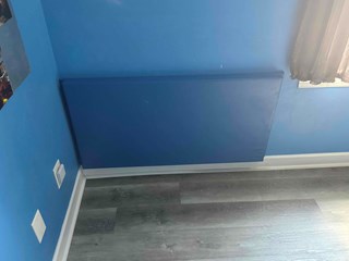 The damaged section has been covered with a smooth blue panel or covering, blending seamlessly with the rest of the wall. The overall wall appears well-maintained and undamaged.
