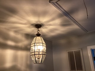 Ceiling fully repaired. The damaged area has been patched, and the ceiling looks smooth and freshly painted. The light fixture is in place, and the ceiling appears clean without any visible signs of damage.