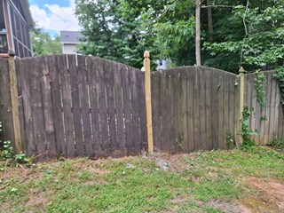 The fence has been straightened, and the sagging gate has been fixed. The overall appearance is more even, with the fence and gate looking properly aligned and sturdy.