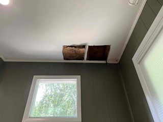 Ceiling with two large holes, exposing the insulation and structure behind the drywall. The area around the holes appears to have some water damage