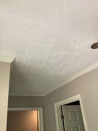Ceiling area after the repair work. The ceiling looks fresh with popcorn texture evenly painted, with no visible stains or damage remaining. 