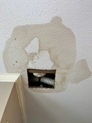  water stain on a ceiling, with some visible damage around the area of a vent. The drywall around the vent is marked by discoloration due to a leak.