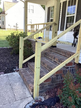  Set of brick steps with a newly installed wooden railing.