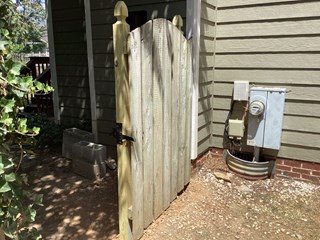 Wood gate with a freshly installed boards, in a more upright position. The wooden fence looks cleaner and well-maintained compared to the first image.