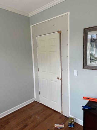After framing in an opening a door frame is unfinished, with the drywall and surrounding area exposed, ready for trim to be added.