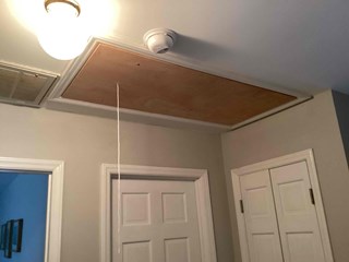 The same area after the repair, with the hatch now fully closed and a new, attic ladder installed. 