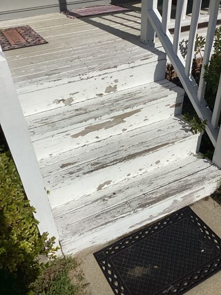 Porch steps steps are damaged and worn with peeling paint.