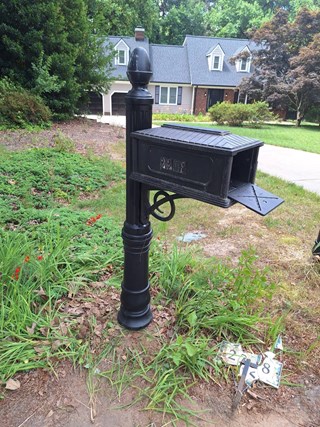 Mailbox and post after being repaired. The mailbox is now securely mounted on a fixed, upright post, looking restored and functional again.