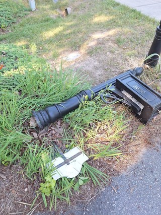 Mailbox and post are damaged, with the post broken and the mailbox lying on the ground.