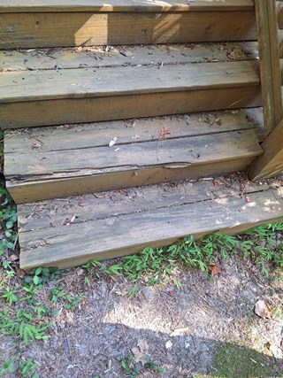 Steps are visibly worn and damaged, with several boards cracked and deteriorated.