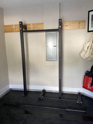 A squat rack/gym equipment has been mounted on to the wall.  A wood supporting structure was added around the electrical panel to reinforce the gym. 