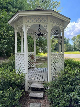 Gazebo is visible with faded and worn wood, especially on the steps and deck. 