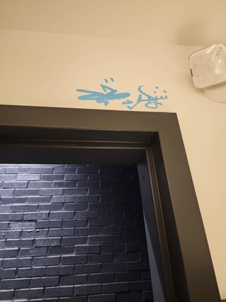 Graffiti is visible on the wall above the door, with blue spray paint tags marking the surface.