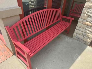 Bench after it has been refinished with a fresh coat of red paint, making it look clean, vibrant, and well-maintained. 
